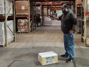 Man standing over box in warehouse with mobile dimensioning unit QBoid